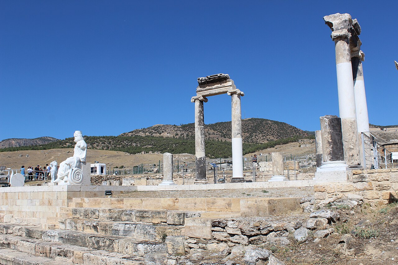 Wide view of the Ploutonion sanctuary at Hierapolis with columns, a statue and surrounding archaeological remains