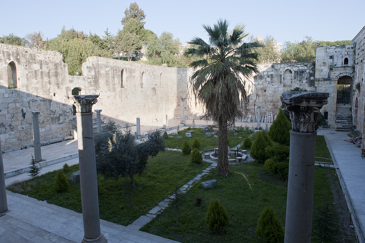 Columns, stone walls and planted central area in the courtyard of Isa Bey Mosque
